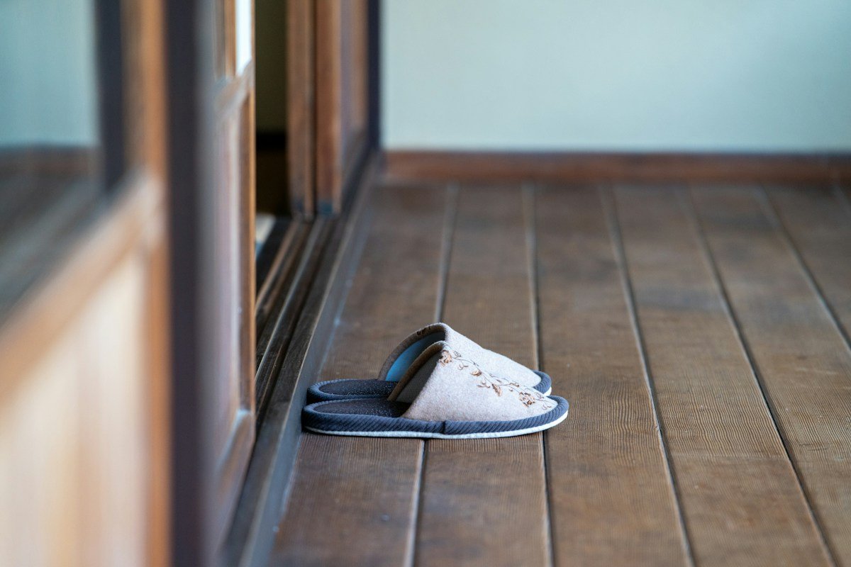 Chaussons posés sur un parquet près d'une porte vitrée
