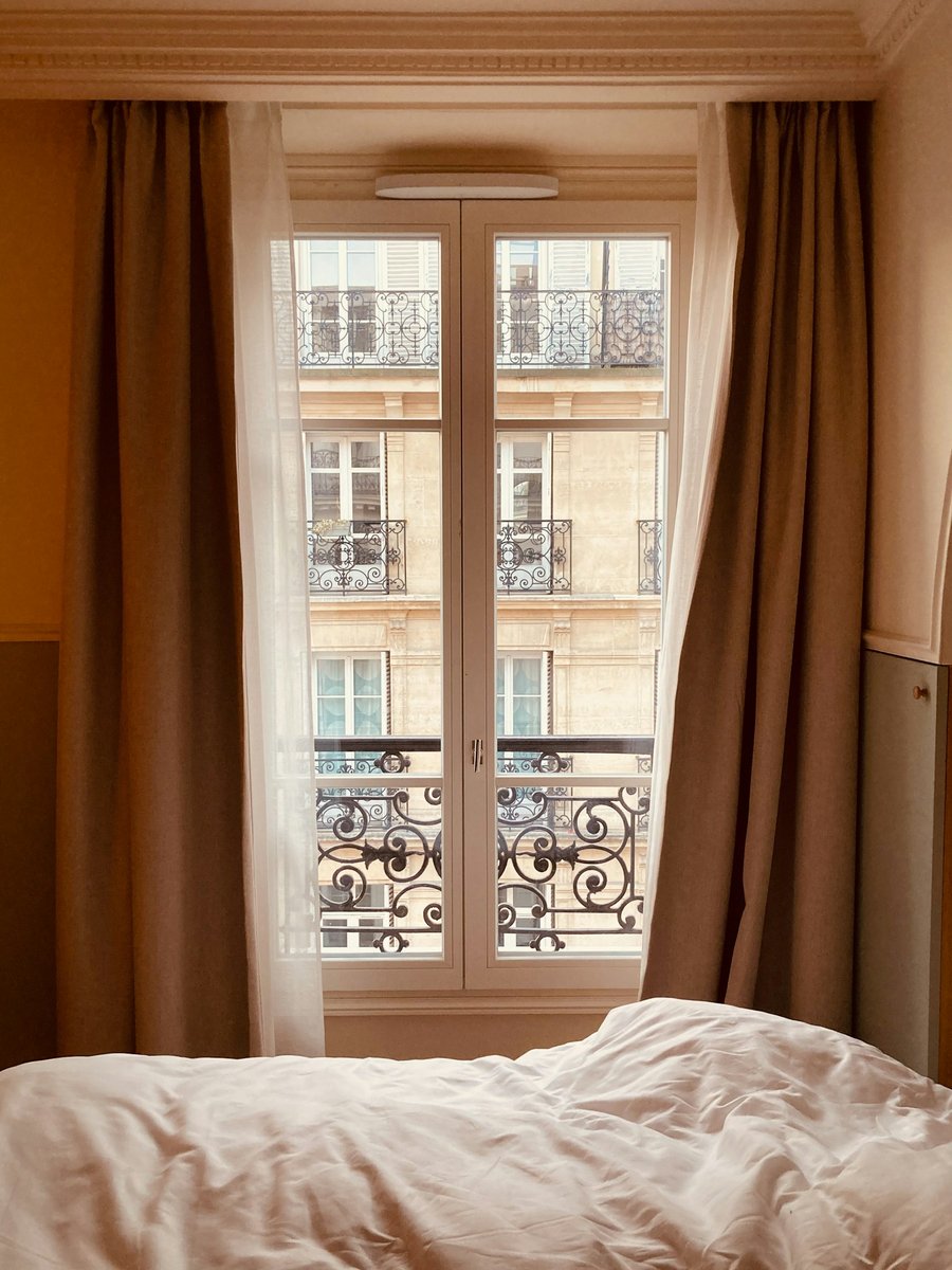 Porte-fenêtre d'un appartement parisien ouverte sur des balcons en fer forgé