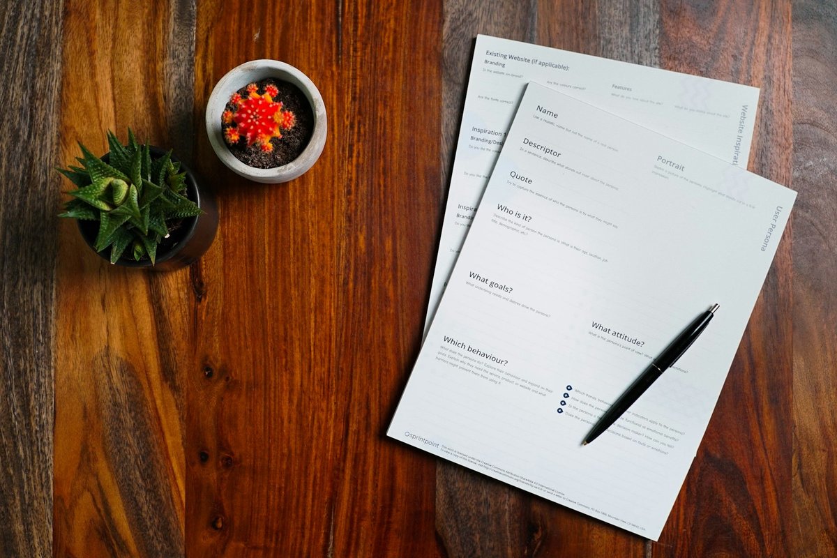 Formulaires et stylo sur une table en bois, plantes grasses